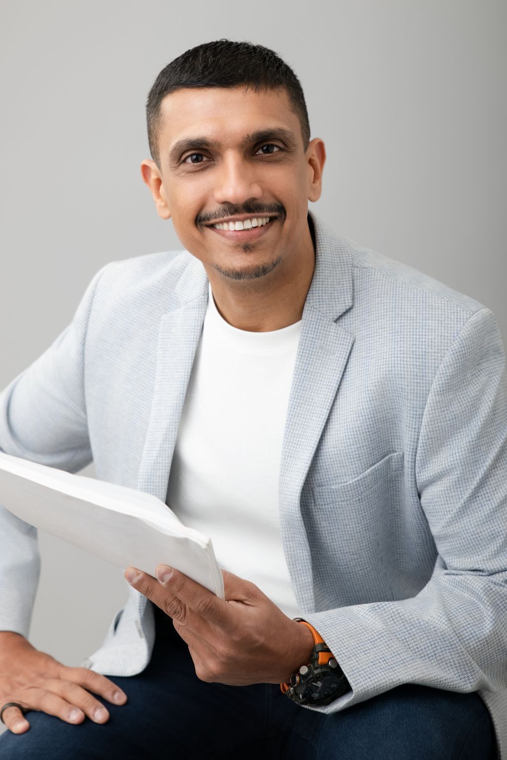 Munaf Shaikh, seated, holding a manuscript